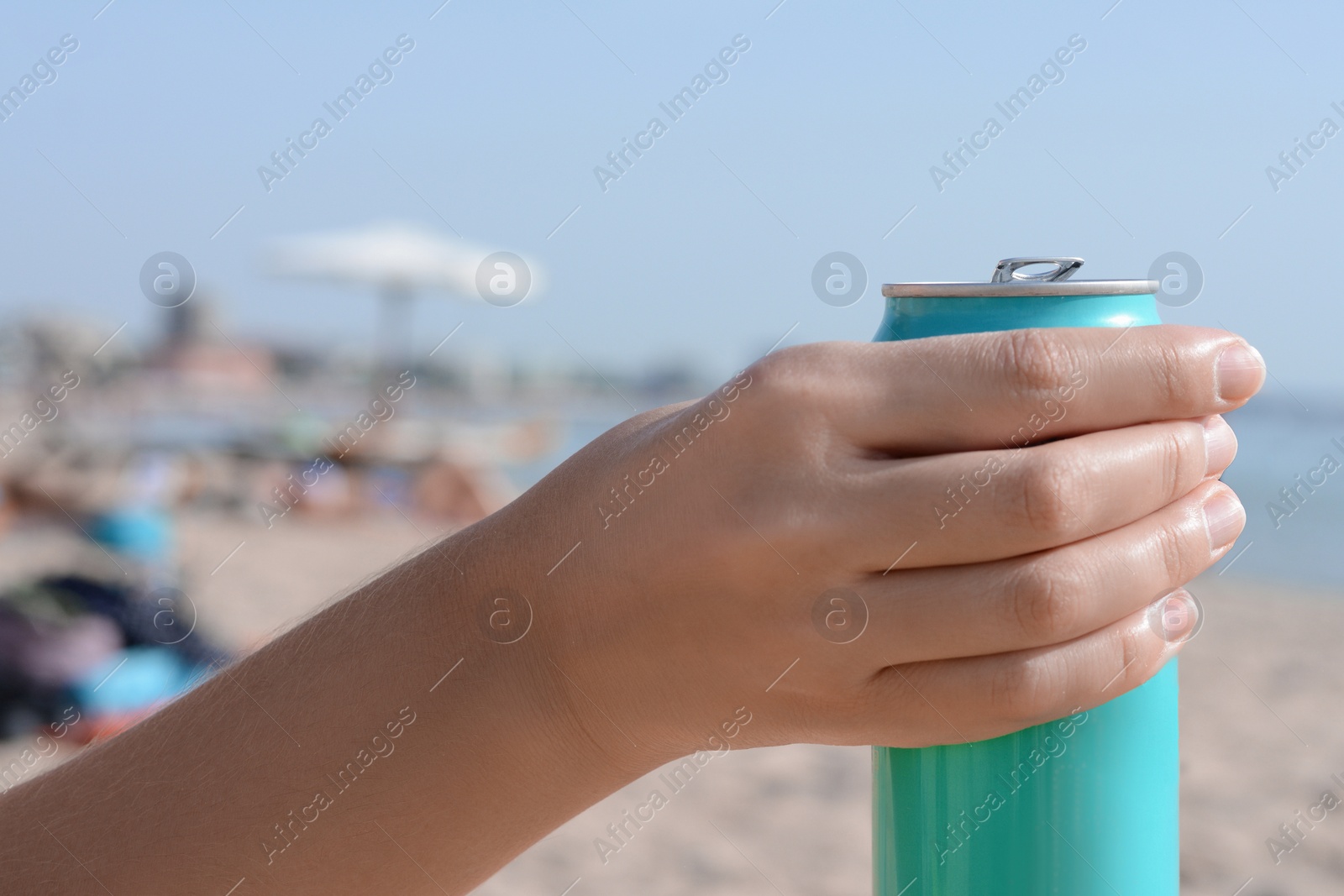 Photo of Woman holding aluminum can with beverage on beach, closeup