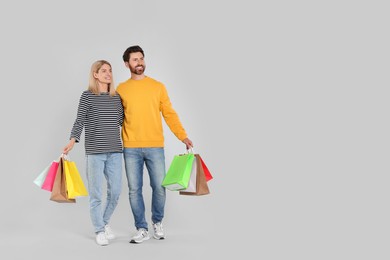 Family shopping. Happy couple with many colorful bags on light grey background. Space for text