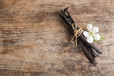 Photo of Flat lay composition with aromatic vanilla sticks and flower on wooden background. Space for text