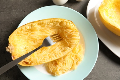 Photo of Plate with cooked spaghetti squash and fork on gray background, top view