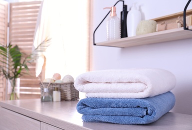 Photo of Stack of fresh towels on cabinet in bathroom. Space for text