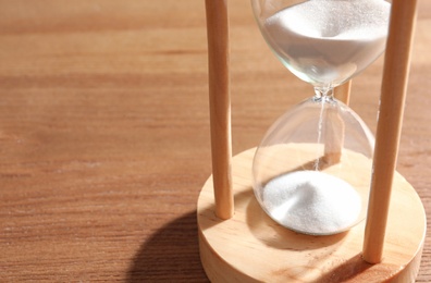 Hourglass with flowing sand on wooden background. Time management