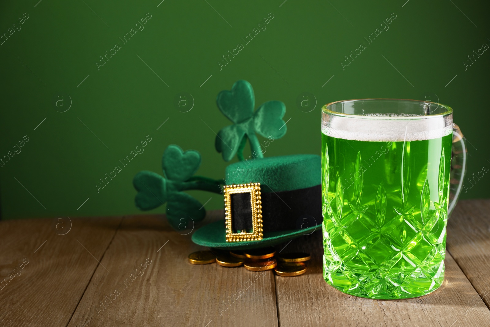 Photo of St. Patrick's day party. Green beer, leprechaun hat, gold and decorative clover leaves on wooden table. Space for text