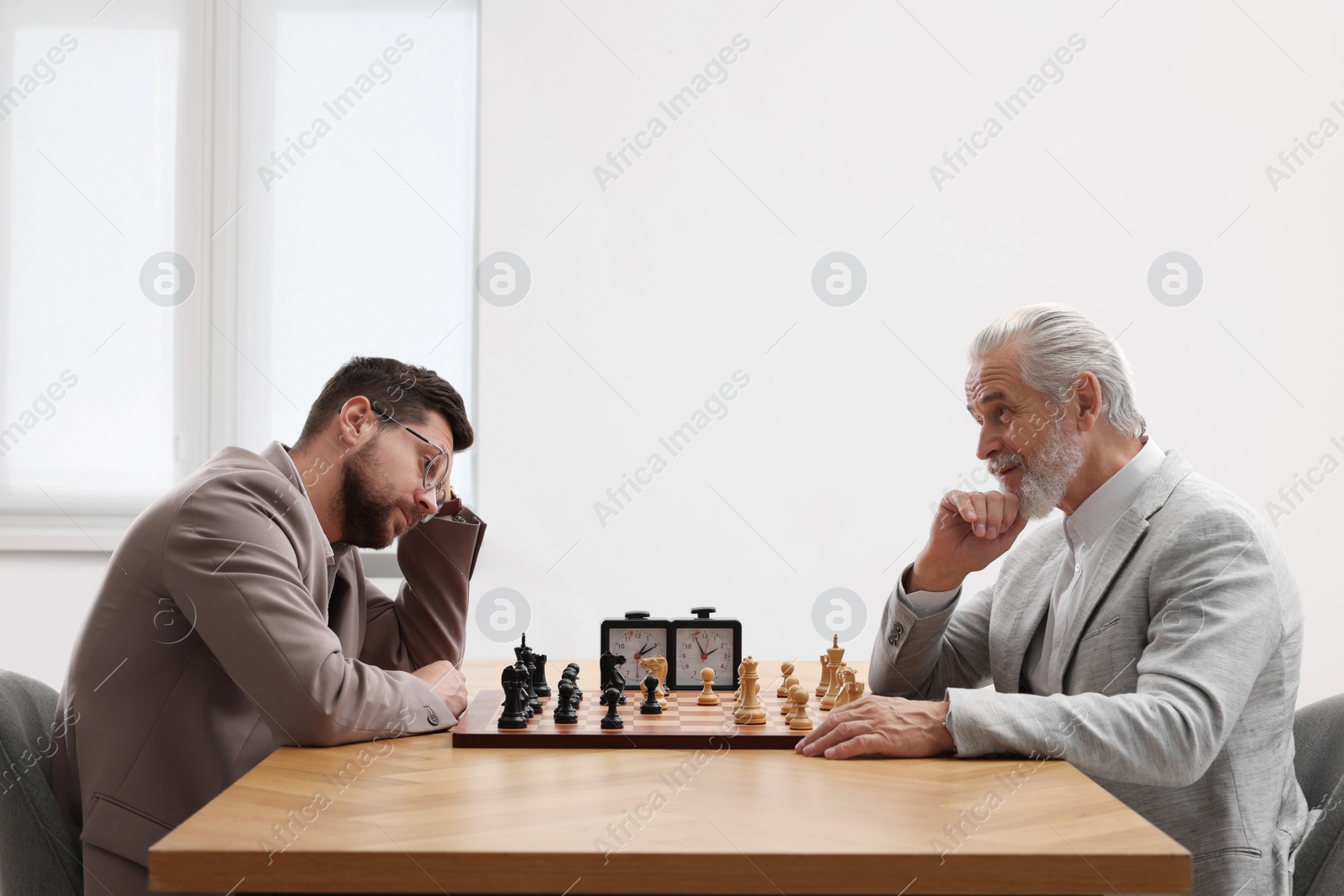 Photo of Men playing chess during tournament at table indoors