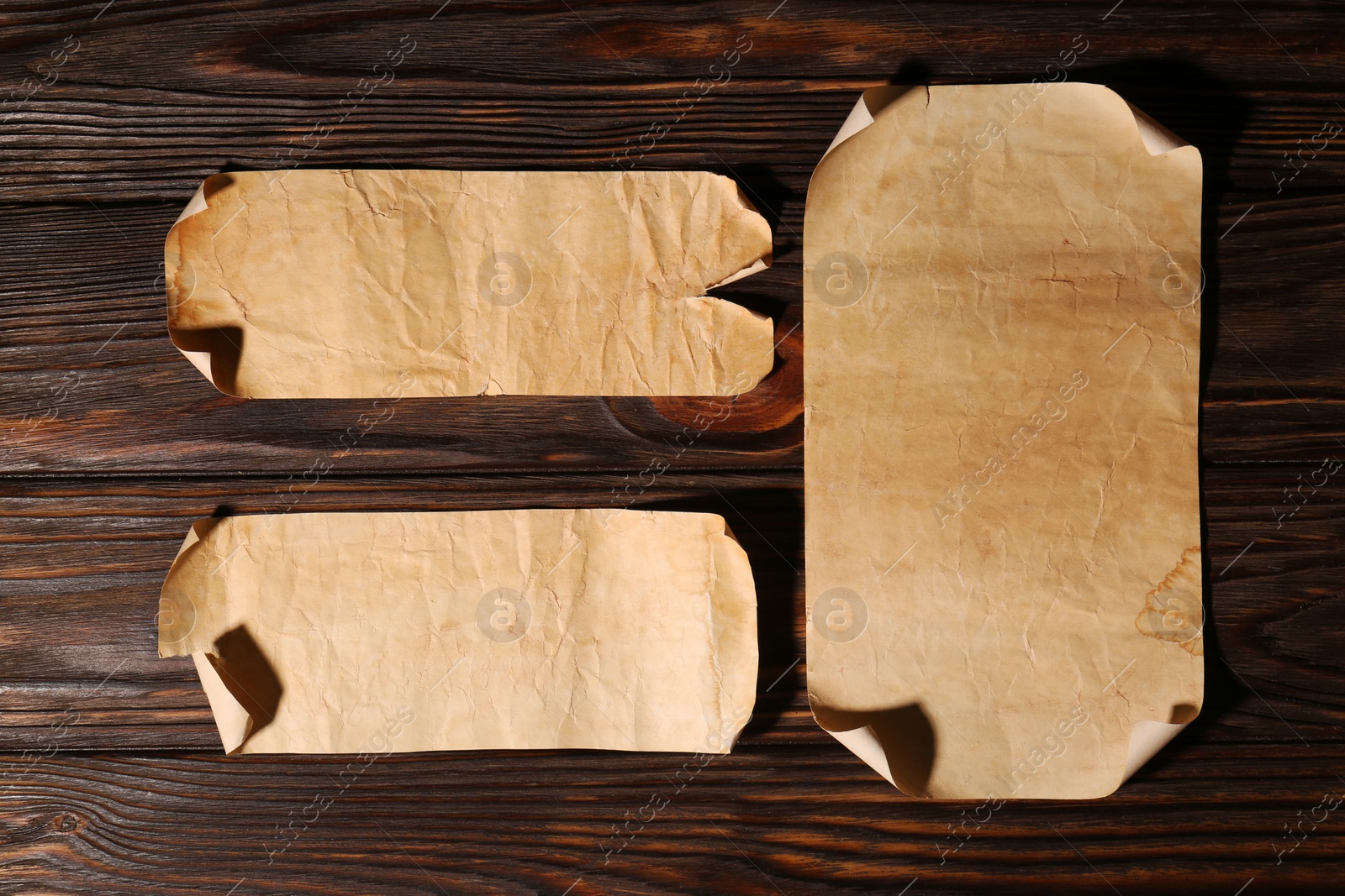 Photo of Sheets of old parchment paper on wooden table, flat lay