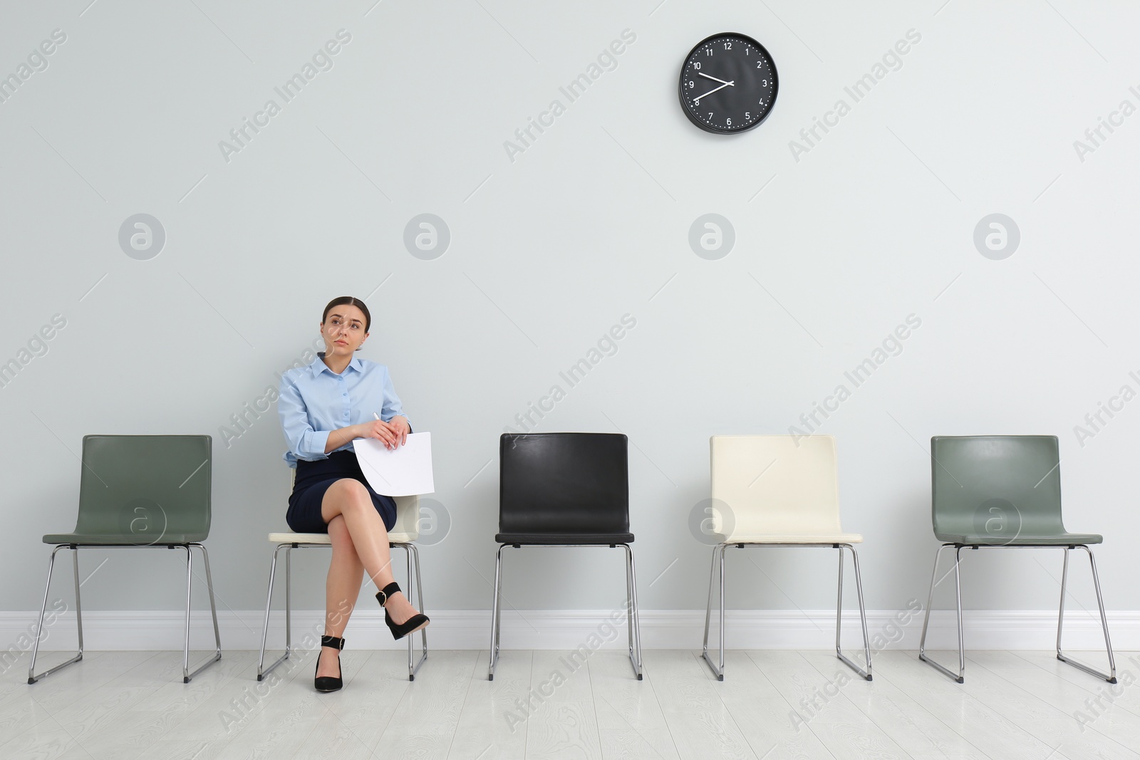 Photo of Young woman with papers waiting for job interview in office hall