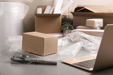Photo of Table with laptop, boxes and bubble wrap in warehouse