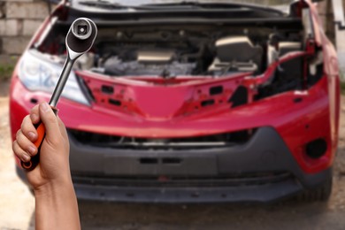 Image of Auto mechanic with socket wrench near broken down car, closeup
