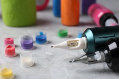 Photo of Professional tattoo machines and inks on light grey table, closeup