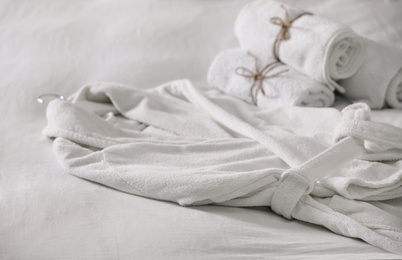 Photo of Clean soft bathrobe and towels on bed