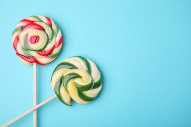 Photo of Colorful lollipops on light blue background, flat lay. Space for text