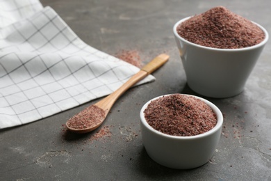 Photo of Ground black salt on grey table. Space for text