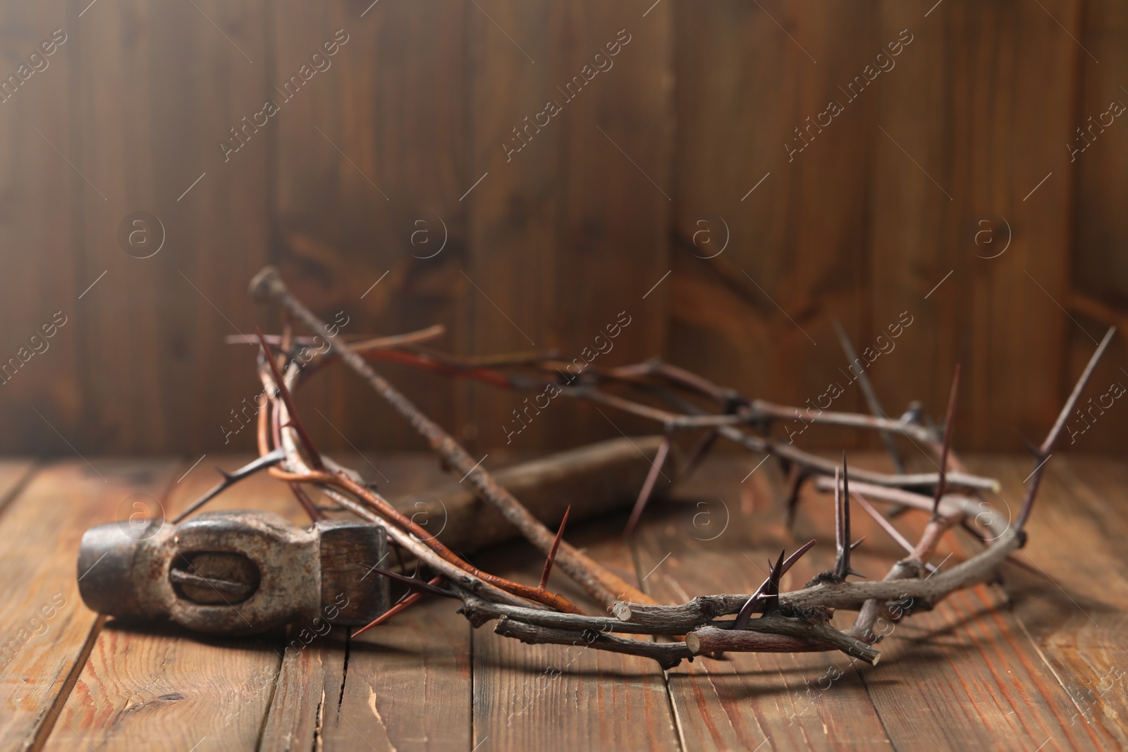 Photo of Crown of thorns, hammer and nail on wooden table, space for text. Easter attributes