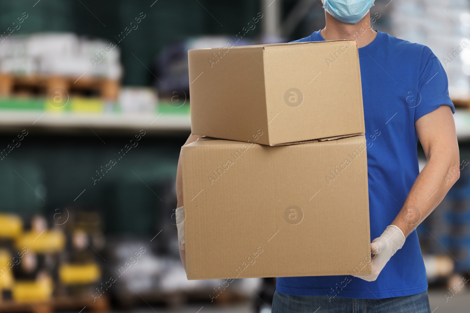 Image of Man wearing uniform and medical mask with cardboard boxes in store, closeup. Wholesale market