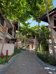 Photo of Paved pathway, trees and buildings in city on sunny day