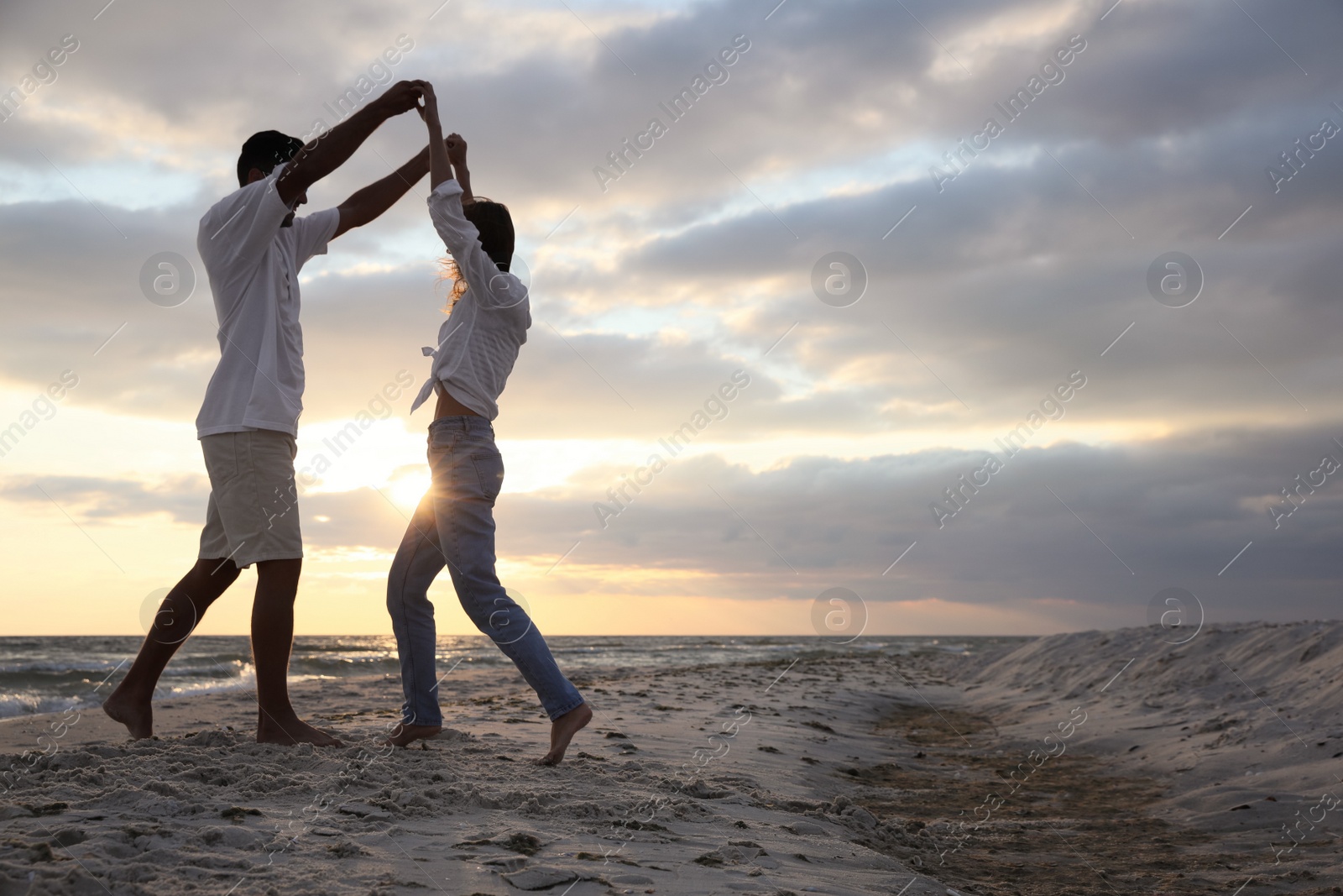 Photo of Happy couple dancing on beach at sunset