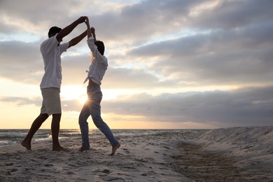 Photo of Happy couple dancing on beach at sunset