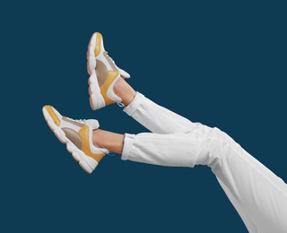 Woman in stylish sport shoes on blue background