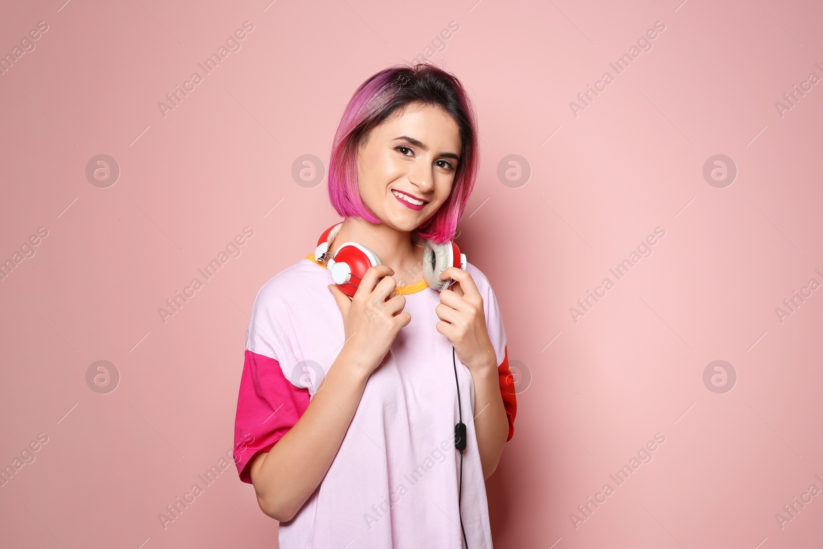 Photo of Young woman with trendy hairstyle and headphones against color background