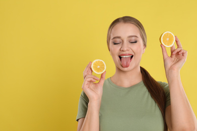 Emotional young woman with cut lemon on yellow background, space for text. Vitamin rich food