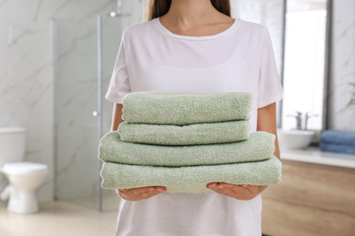 Woman holding fresh towels in bathroom, closeup