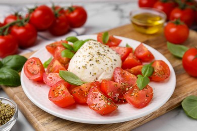 Photo of Tasty salad Caprese with mozarella, tomatoes and basil on table, closeup