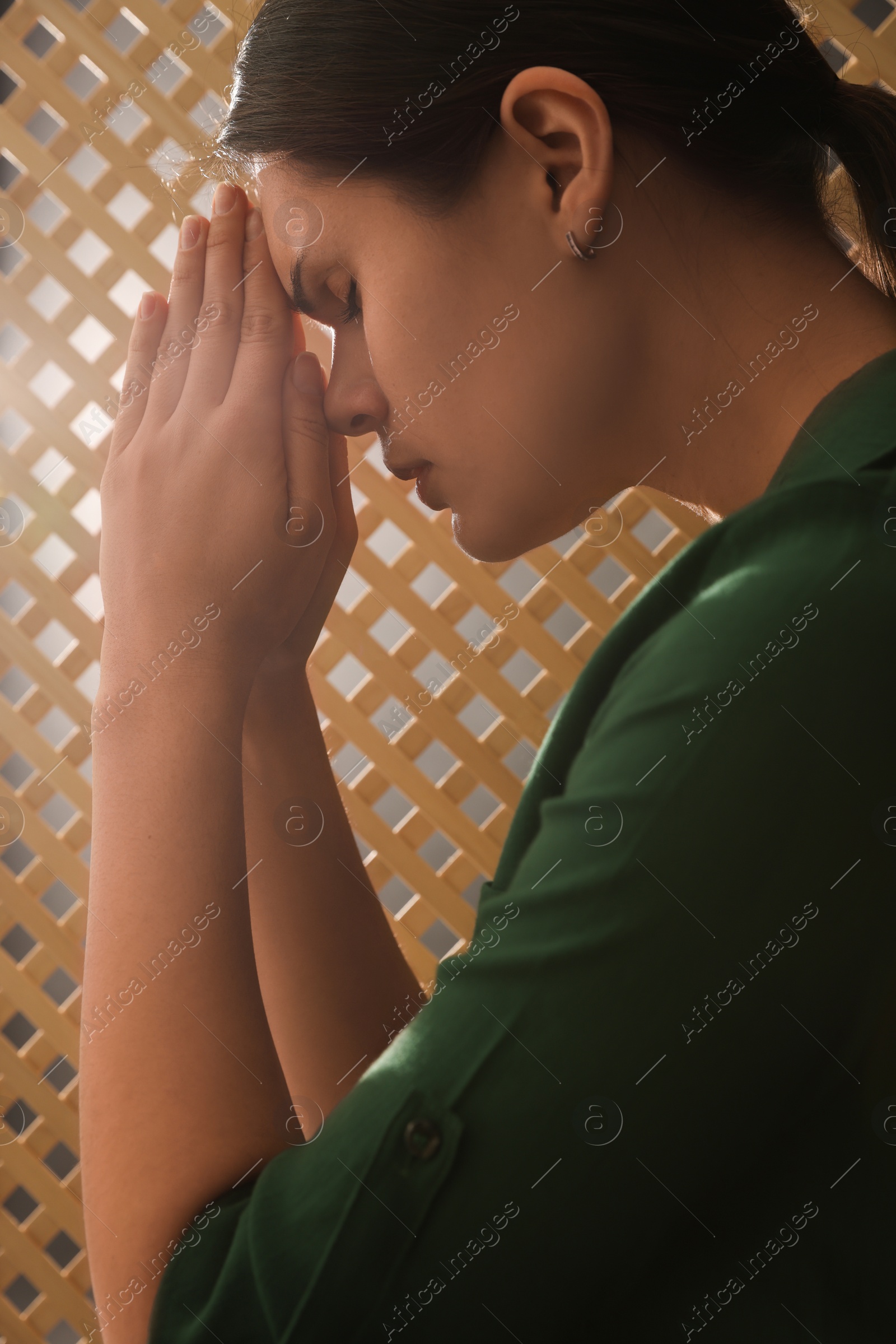 Photo of Woman praying to God during confession in booth