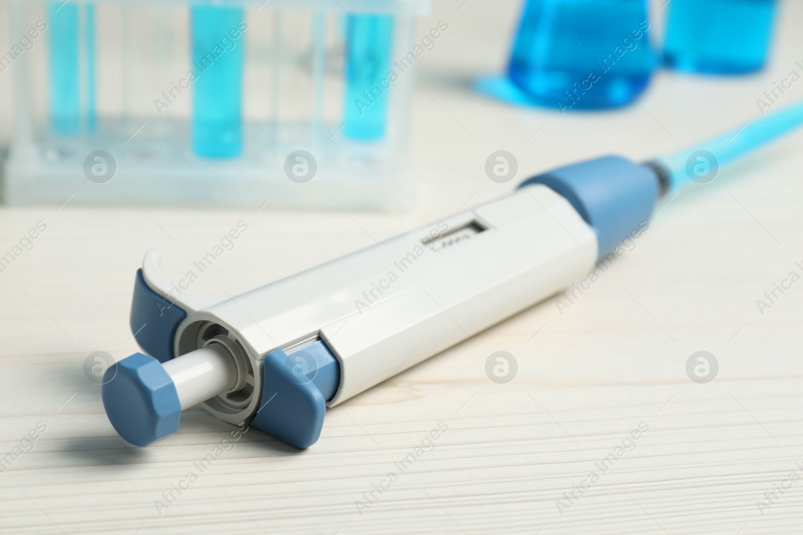 Photo of Laboratory analysis. Micropipette with liquid on white wooden table, closeup