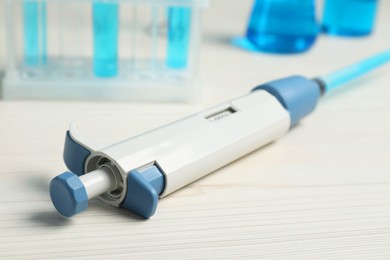 Laboratory analysis. Micropipette with liquid on white wooden table, closeup