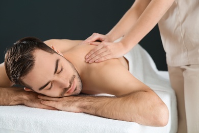 Photo of Handsome man receiving back massage on black background. Spa service