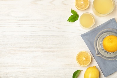 Photo of Flat lay composition with freshly squeezed lemon juice and space for text on wooden background