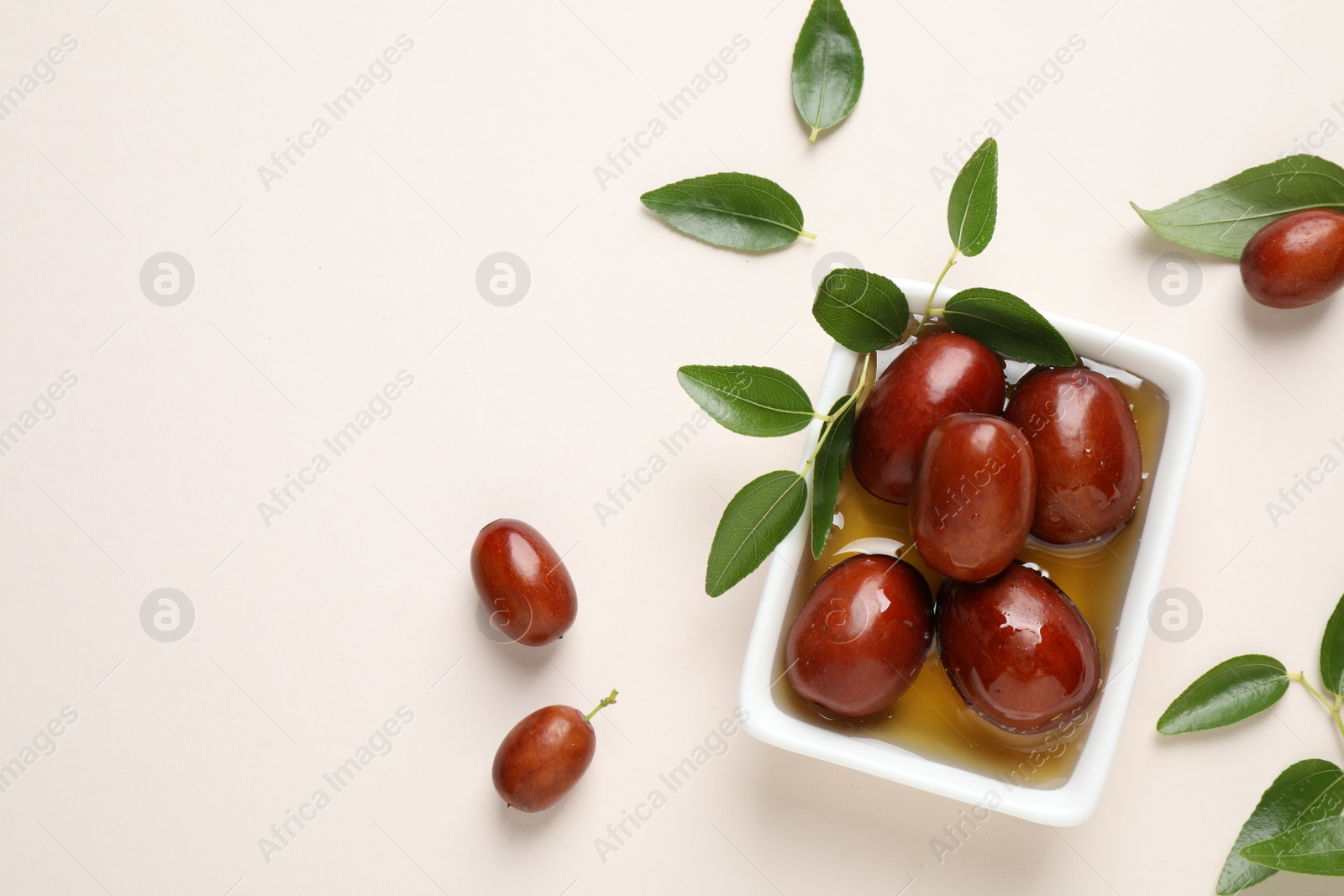 Photo of Sauce boat with jojoba oil and seeds on light background, flat lay. Space for text