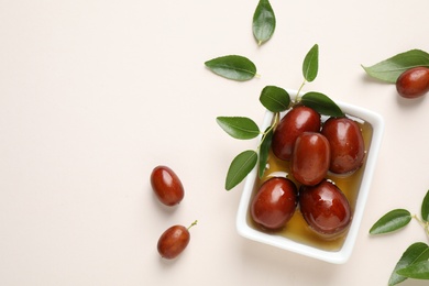 Sauce boat with jojoba oil and seeds on light background, flat lay. Space for text