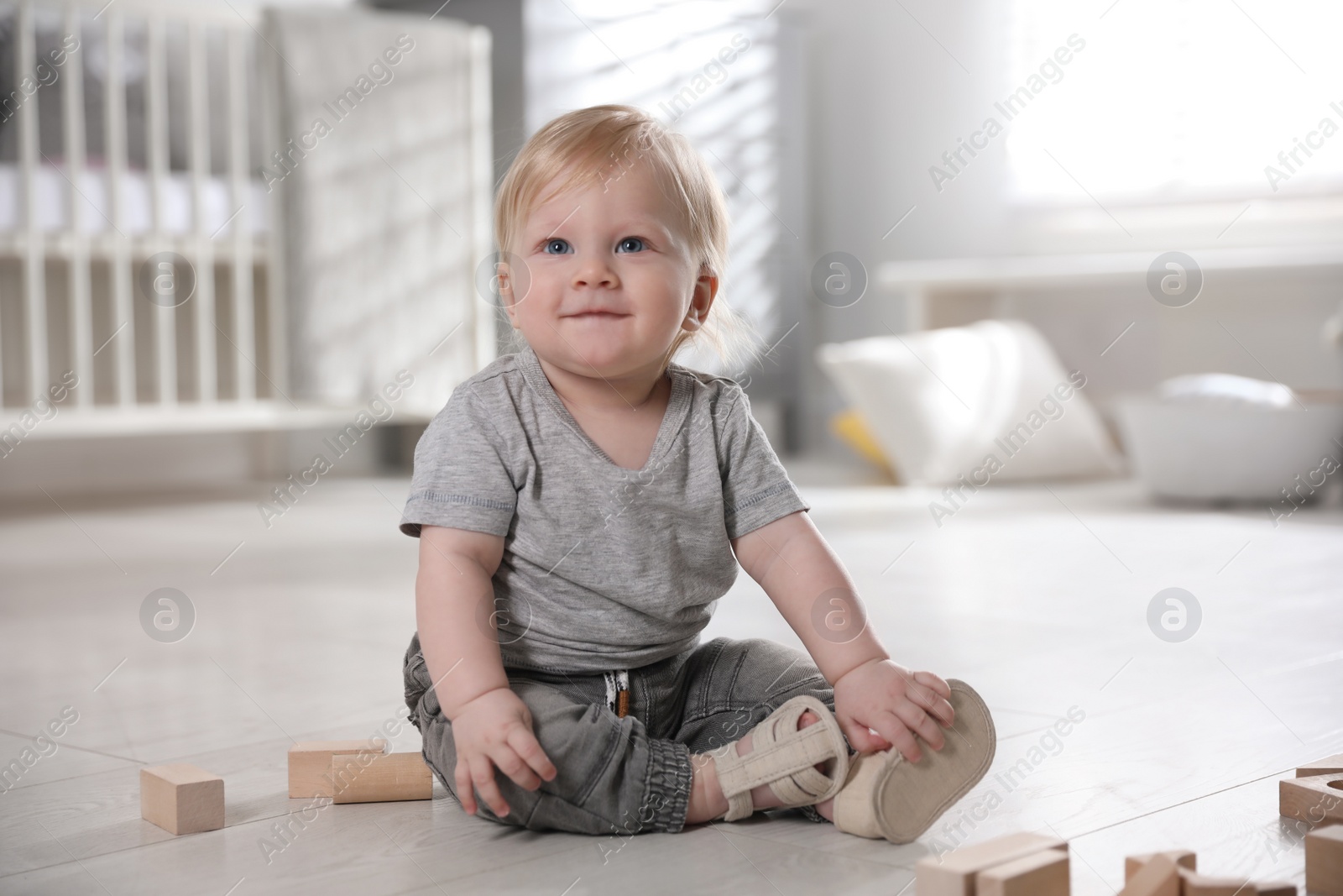 Photo of Adorable little baby with wooden blocks on floor at home