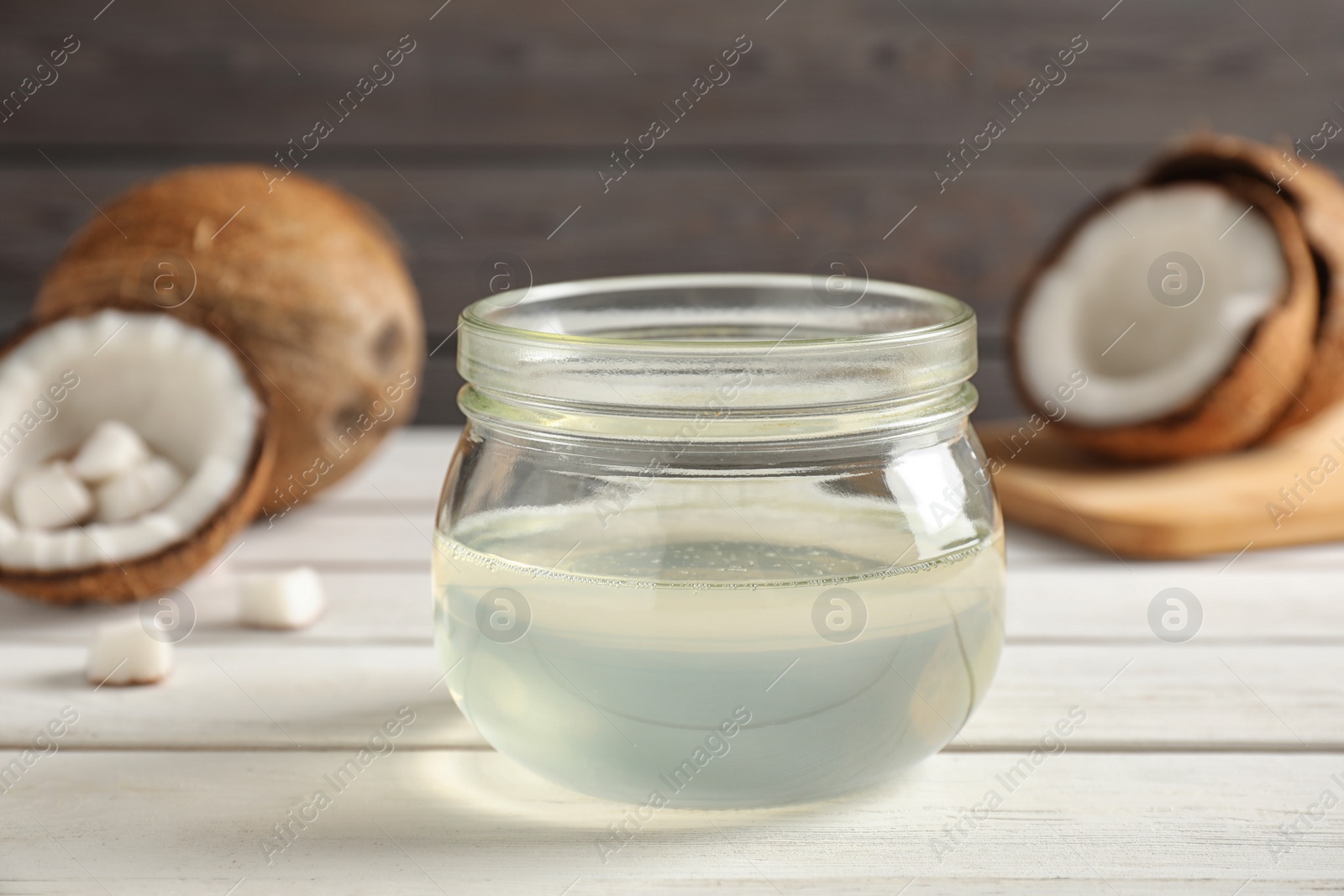 Photo of Coconut oil on white wooden table, closeup