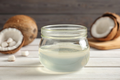 Photo of Coconut oil on white wooden table, closeup