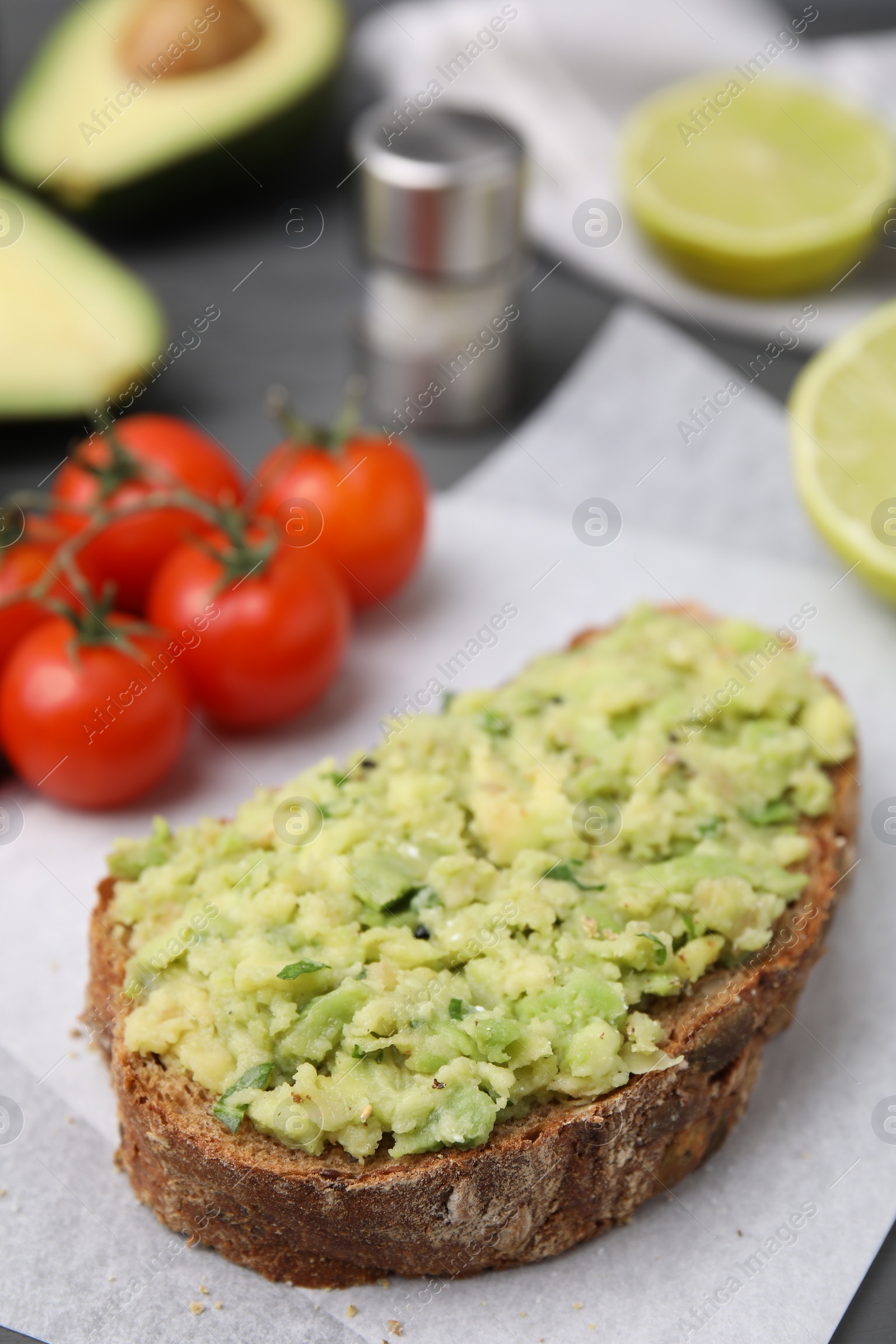 Photo of Delicious sandwich with guacamole on parchment paper, closeup