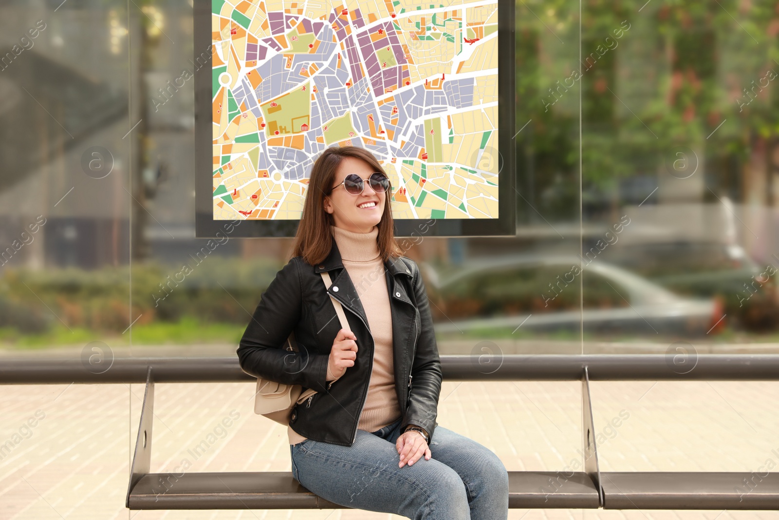 Image of Young woman waiting for public transport at bus stop