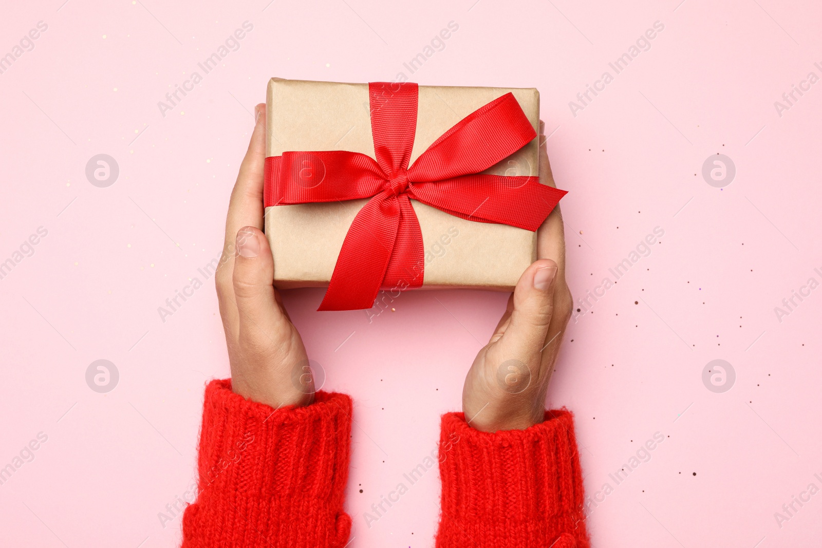 Photo of Young woman holding Christmas gift on pink background, top view