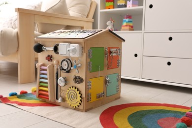 Photo of Busy board house on floor indoors. Baby sensory toy