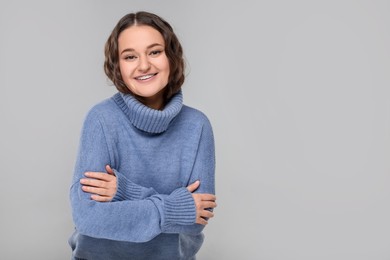 Photo of Smiling woman with dental braces in warm sweater on grey background. Space for text