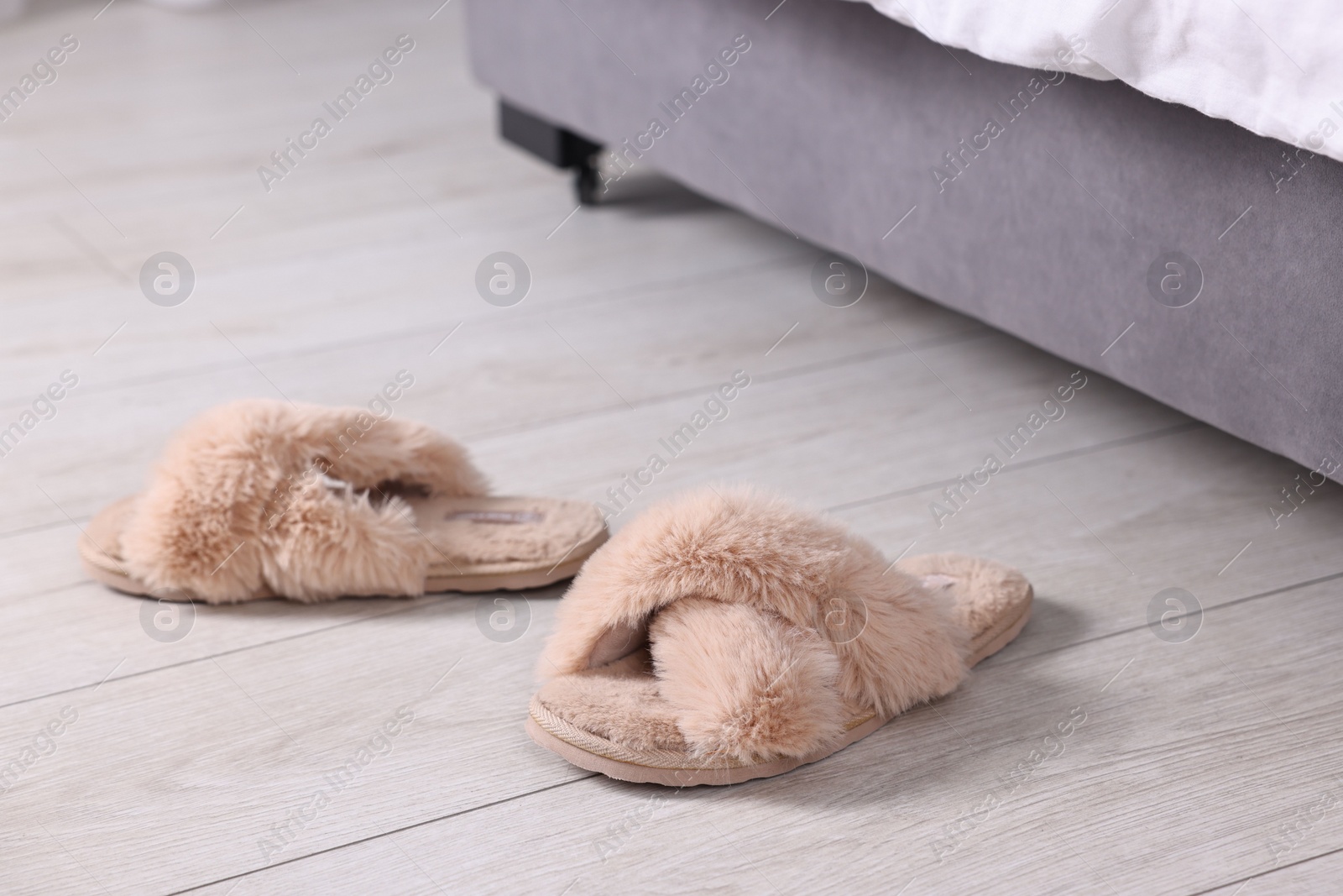 Photo of Beige soft slippers on light wooden floor at home