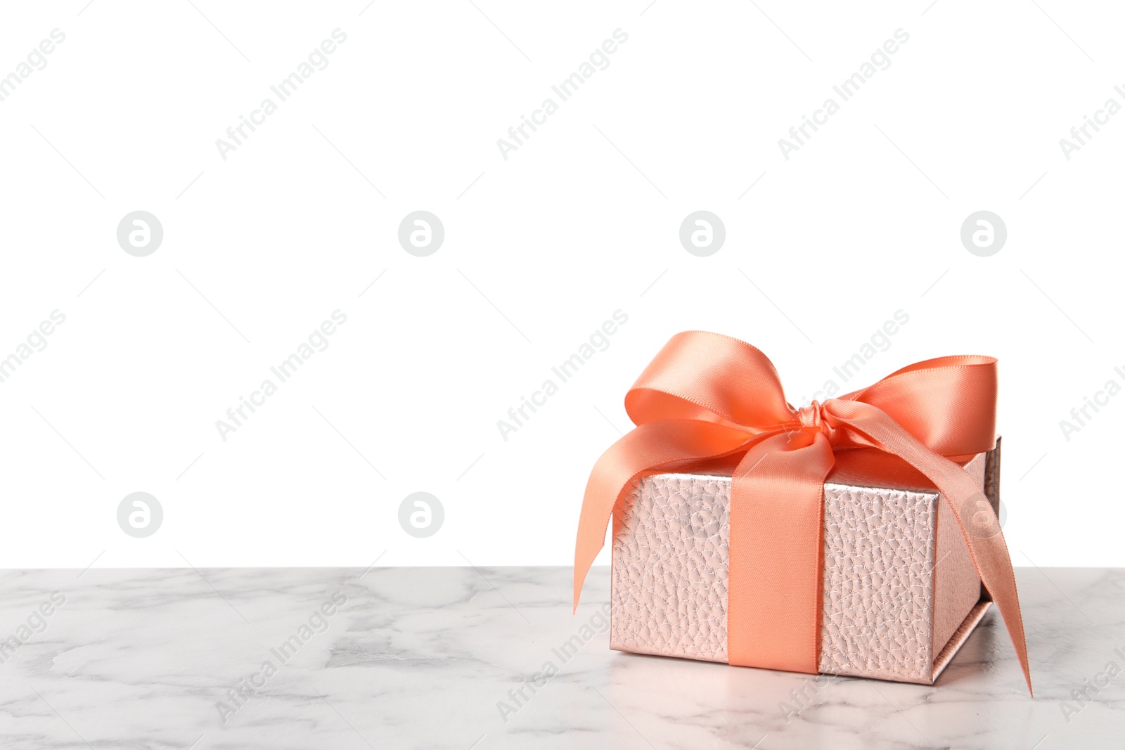 Photo of Pink gift box with ribbon and bow on white marble table. Space for text