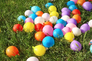 Photo of Lots of colorful water bombs on green grass outdoors