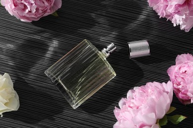 Photo of Luxury perfume and floral decor on dark background, flat lay