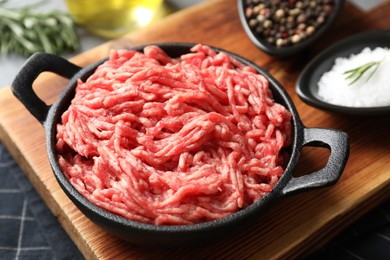 Photo of Raw ground meat in bowl and spices on table, closeup