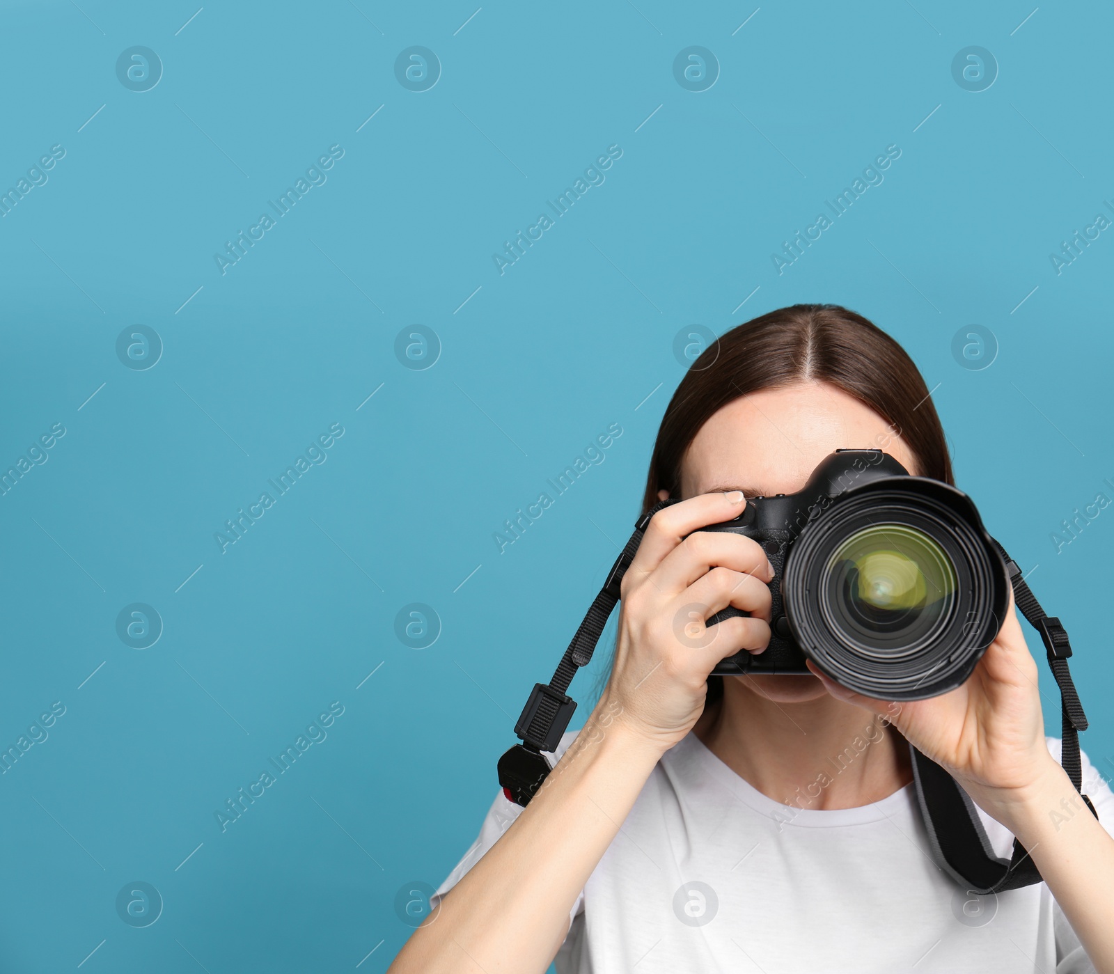 Photo of Professional photographer taking picture on light blue background. Space for text