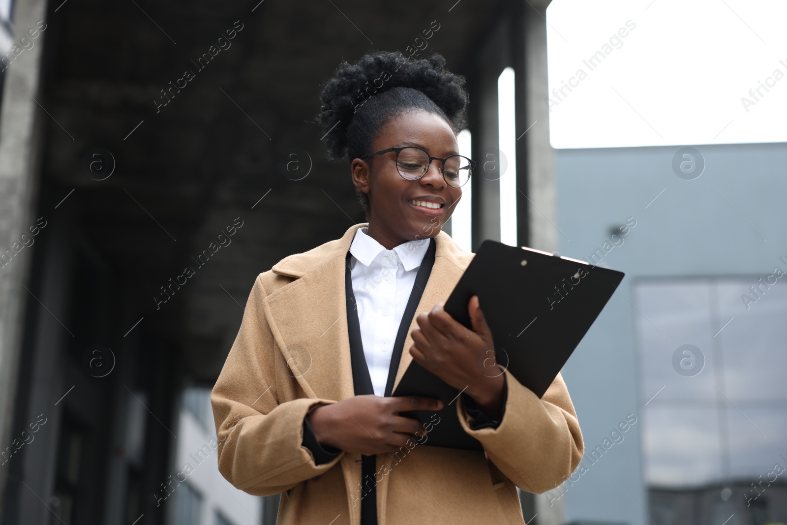 Photo of Happy woman with clipboard outdoors. Lawyer, businesswoman, accountant or manager