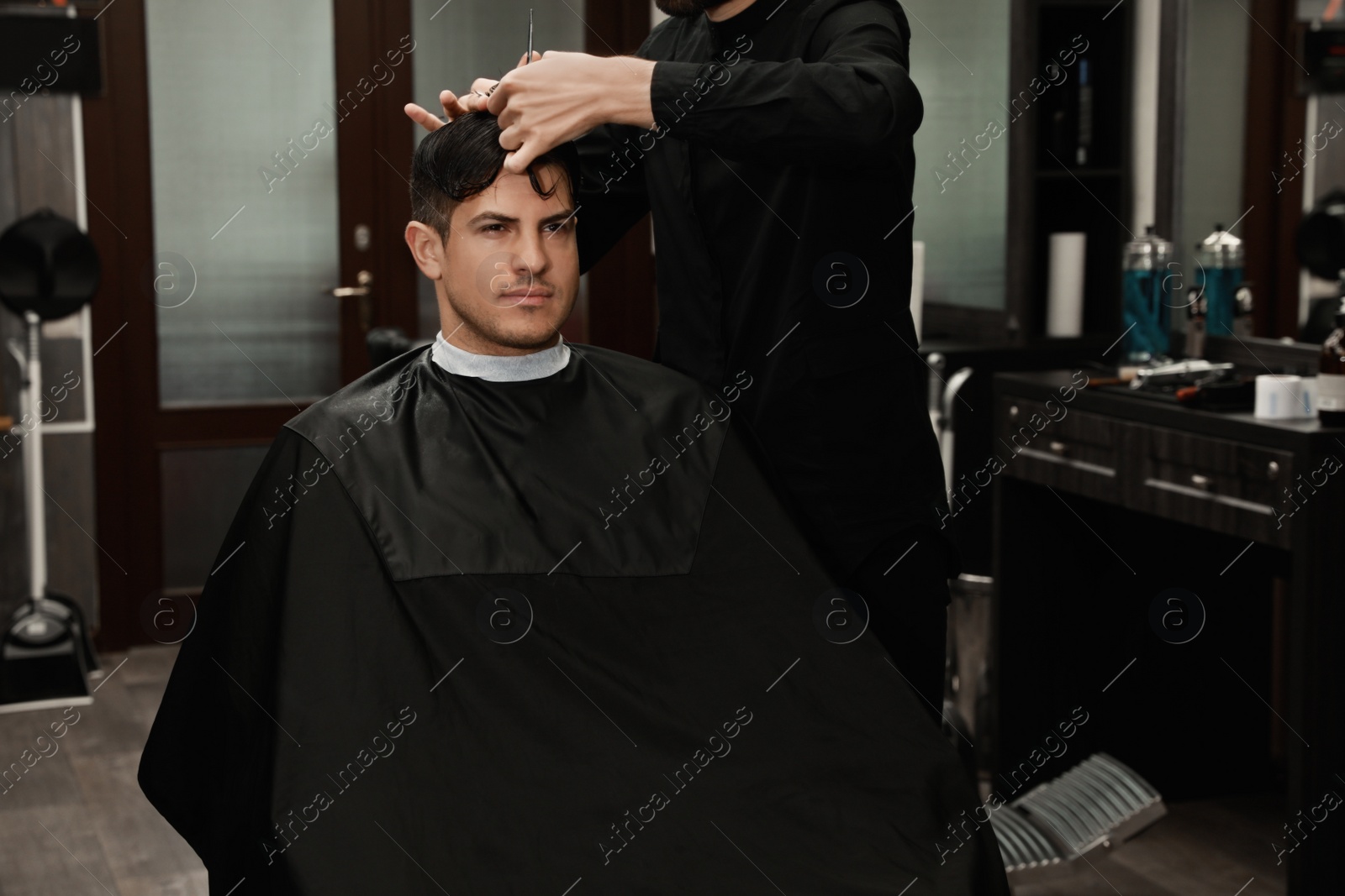 Photo of Professional hairdresser making stylish haircut in salon, closeup