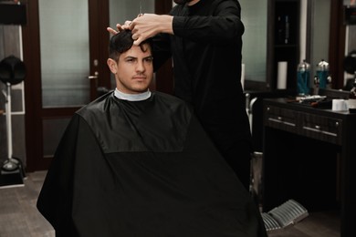 Photo of Professional hairdresser making stylish haircut in salon, closeup